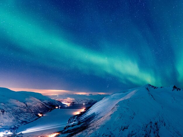 Disparo vertical de un paisaje invernal con la reflexión de la aurora boreal sobre el lago congelado, Tromso