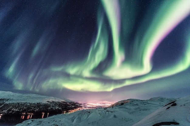 Disparo vertical de un paisaje de invierno nocturno con la reflexión de la aurora boreal sobre el río