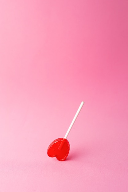 Foto gratuita disparo vertical de una paleta en forma de corazón sobre un fondo de color rosa