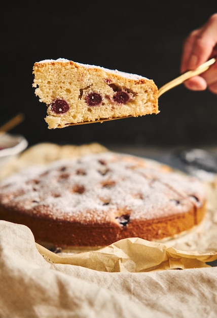 Disparo vertical de un pastel de cerezas con azúcar en polvo e ingredientes en negro