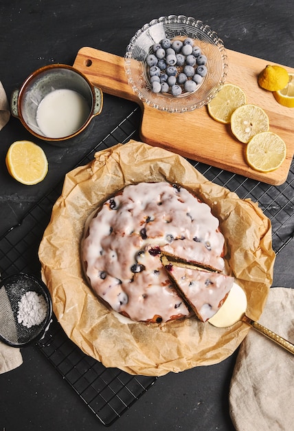 Disparo vertical de un pastel de cerezas con crema e ingredientes en el lado negro