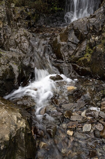 Disparo vertical de una pequeña cascada que fluye desde una montaña empinada