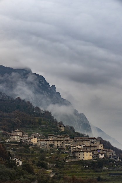 Disparo vertical de un pequeño pueblo italiano en una montaña rodeada de niebla