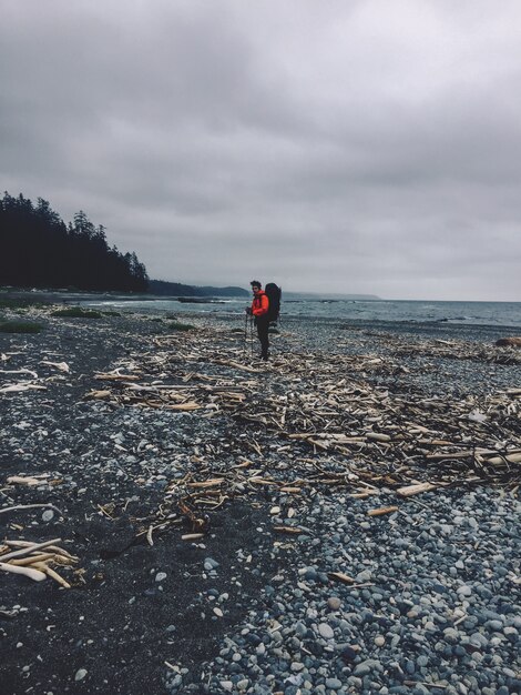 Disparo vertical de una persona de pie en una playa rocosa junto al océano