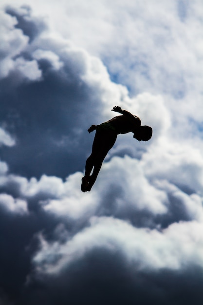 Disparo vertical de una persona saltando en el aire con un cielo borroso