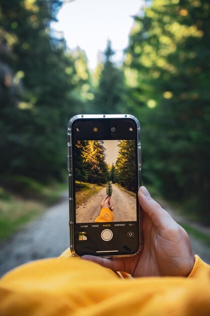 Disparo vertical de una persona tomando una foto de una hoja con una cámara de teléfono celular