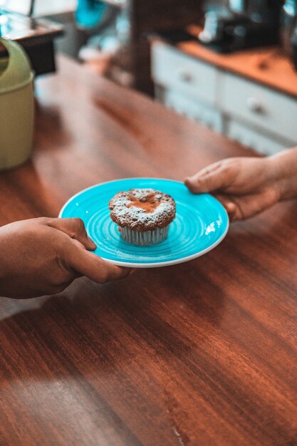 Disparo vertical de personas sosteniendo un plato de una sabrosa galleta en el café