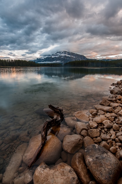 Disparo vertical de las piedras en el lago transparente bajo el oscuro cielo nublado