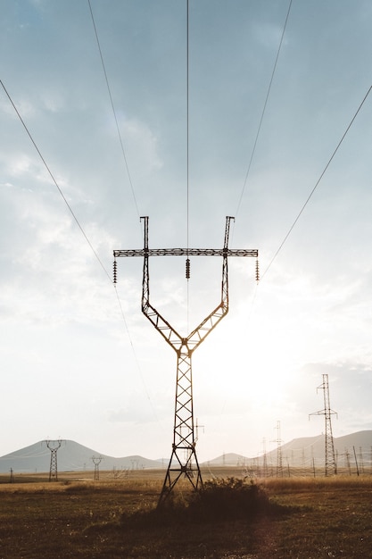 Disparo vertical de un poste eléctrico con rejas metálicas en la parte superior bajo un cielo nublado