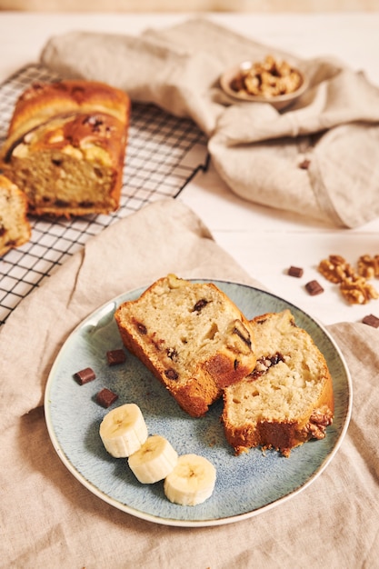 Disparo vertical de rebanadas de delicioso pan de plátano con trozos de chocolate y nueces en una placa