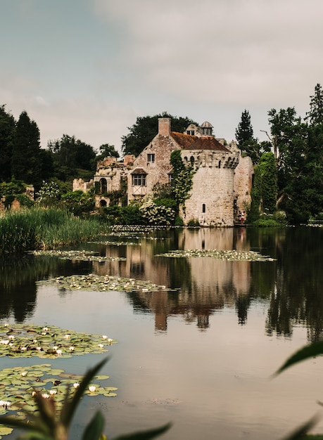 Disparo vertical del reflejo de un antiguo castillo en un hermoso estanque rodeado de árboles