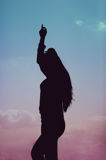 Disparo vertical de una silueta de una mujer bailando durante una hermosa puesta de sol