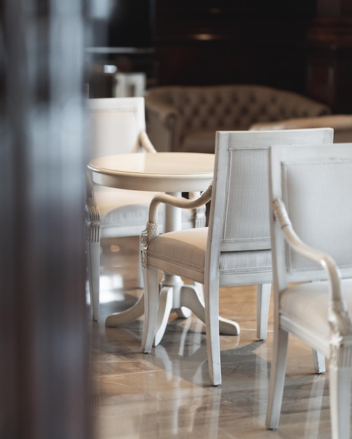 Disparo vertical de simples sillas y mesas blancas en un restaurante con un fondo borroso