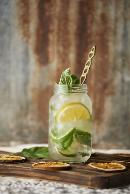 Disparo vertical de un tarro de cristal bebida mojito con hojas de menta y rodajas de limón en una bebida de madera