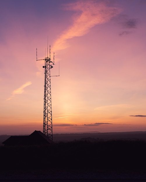 Disparo vertical de una torre de telecomunicaciones en un campo bajo el impresionante cielo, perfecto para papel tapiz