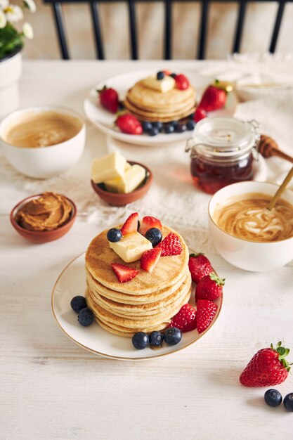 Disparo vertical de tortitas de tofu vegano con frutas cerca de jarabe y café