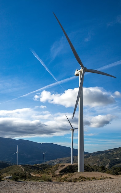 Disparo vertical de varios molinos de viento eléctricos blancos sobre una colina