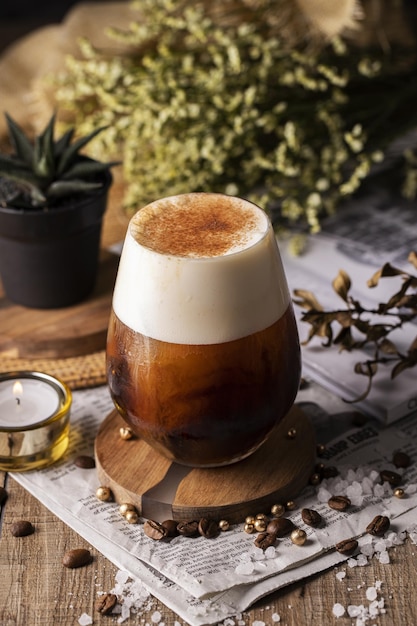 Foto gratuita disparo vertical de un vaso de café con crema en una mesa bellamente decorada