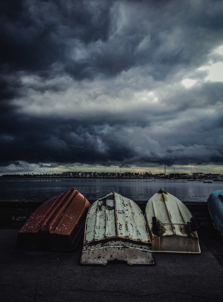 Foto gratuito disparo vertical de viejos barcos de pesca al revés bajo el cielo sombrío