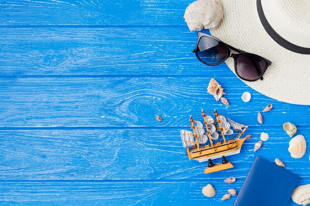 Disposición de conchas marinas cerca de barco de juguete y gafas de sol con sombrero