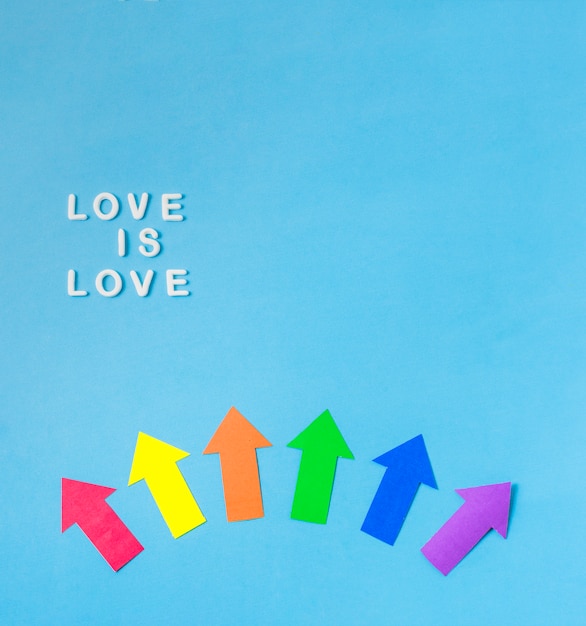 Foto gratuita disposición de las flechas de papel en colores lgbt y el amor es palabras de amor