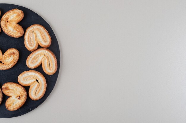 Disposición de galletas hojaldradas en un tablero negro sobre fondo blanco.