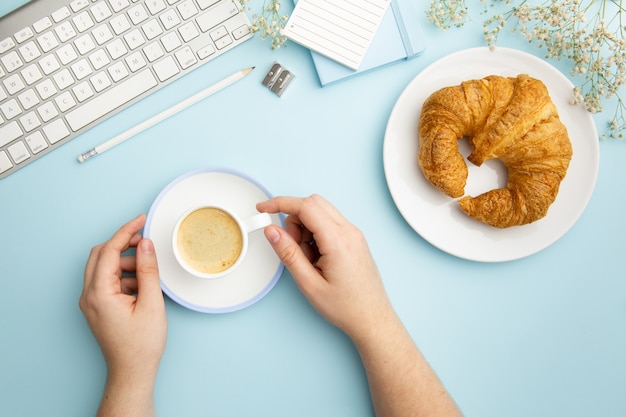 Disposición de lugar de trabajo plano sobre fondo azul con comida de desayuno