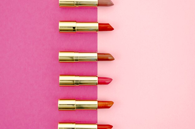 Disposición minimalista de lápices labiales sobre fondo rosa