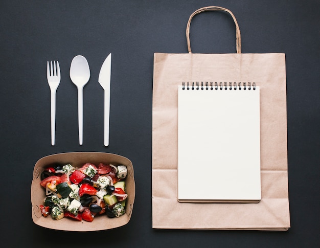 Disposición plana con cuaderno en bolsa de papel