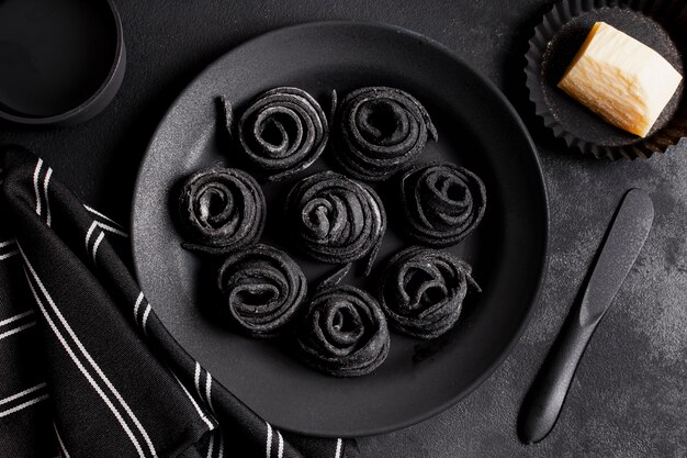 Disposición plana de deliciosa comida negra en la mesa oscura