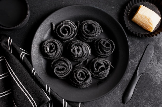 Disposición plana de deliciosa comida negra en la mesa oscura