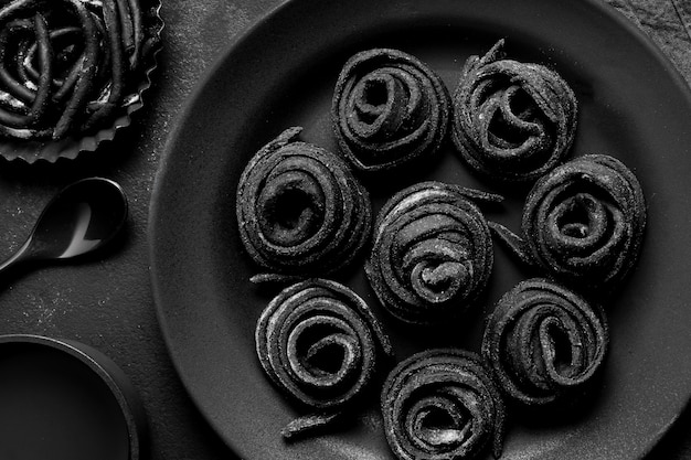 Disposición plana de deliciosa comida negra en plato oscuro y mesa