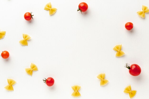 Disposición plana de farfalle crudo sin cocer con tomates con espacio de copia