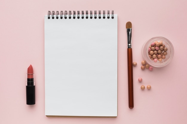 Disposición plana con productos de maquillaje y cuaderno