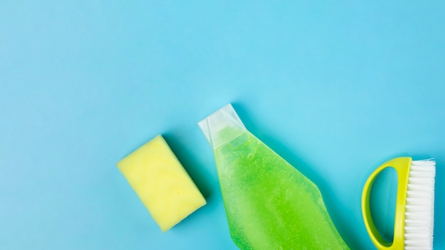 Disposición de la vista superior con detergente verde, esponja y cepillo