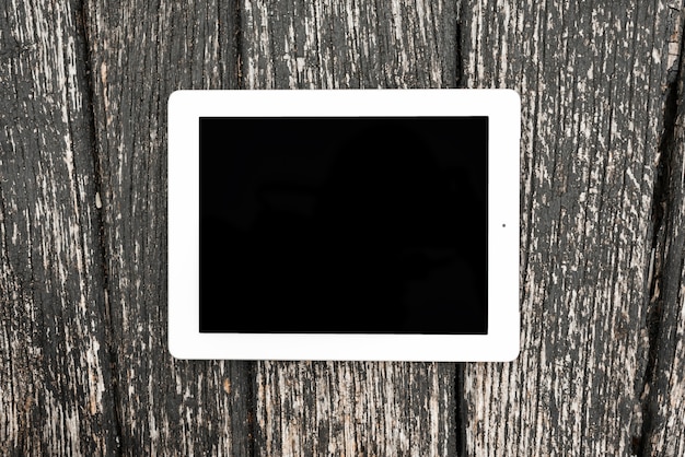 Dispositivo digital en blanco de la tableta en el contexto texturizado de madera