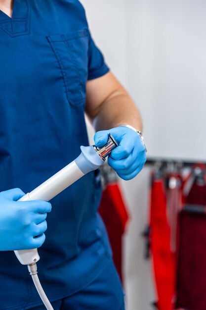 Dispositivo de terapia de ondas de choque con manos de médico con guantes de goma