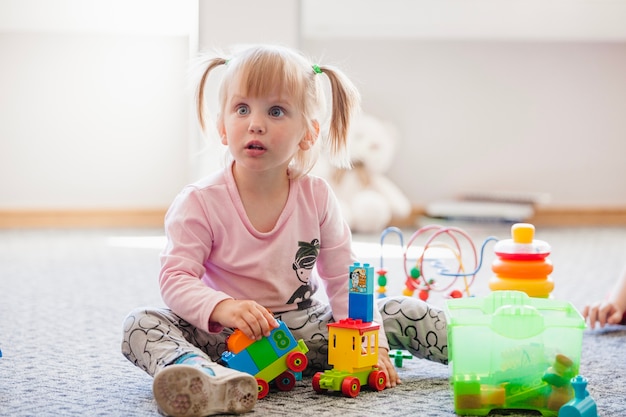 Distraído niña con juguetes mirando a otro lado