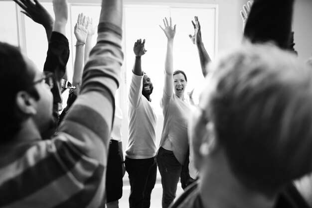 Diversidad de trabajo en equipo con las manos levantadas.