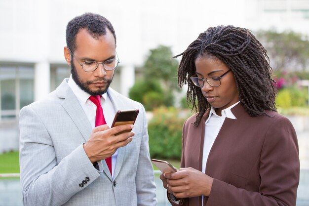 Diversos colegas de negocios que usan teléfonos inteligentes