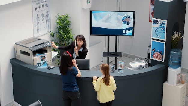 Diversos grupos de pacientes que esperan asistir a una cita médica, sentados en el ajetreado mostrador de recepción del hospital. Personas con seguro de salud que se examinan con un especialista. Disparo de mano.