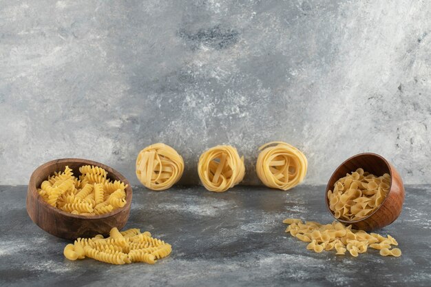 Diversos tipos de pasta cruda en cuencos de madera.