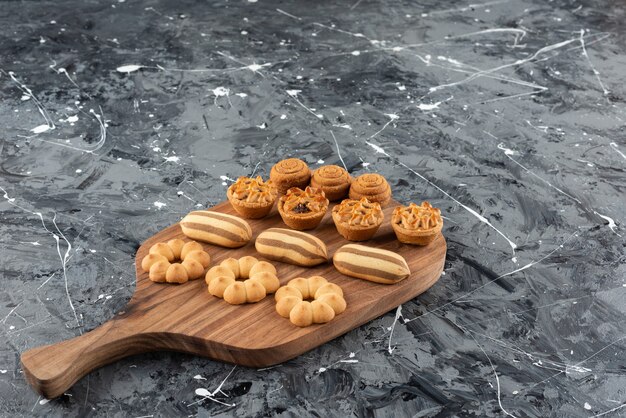 Diversos tipos de pasteles dulces en una tabla para cortar madera