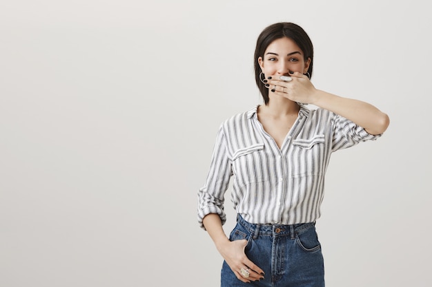 Divertida atractiva morena con sonrisa, mantenga la mano en la boca