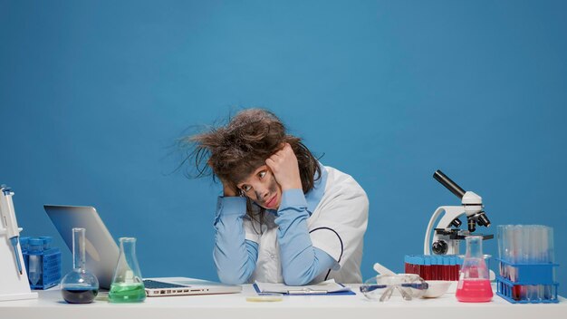 Divertida científica loca que trabaja en una computadora portátil y actúa como una loca, haciendo expresiones faciales tontas y tontas y tirando de su cabello. Un especialista tonto y divertido que se siente confundido y desesperado ante la cámara.