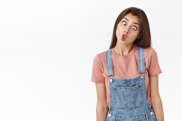 Divertida y linda mujer tonta haciendo caras raras locas haciendo muecas doblando los labios como peces y entrecerrando los ojos cambiando de pie de fondo blanco divirtiéndose como jugar a las charadas durante el día de acción de gracias