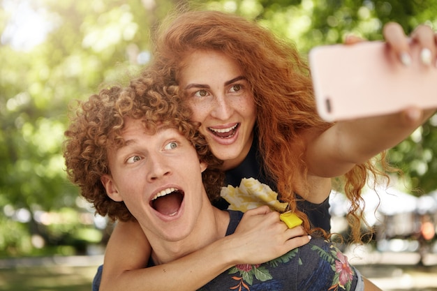 Foto gratuita divertida pareja de enamorados caminando en la calle posando para selfie