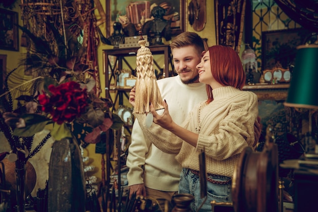 Divertido. Familia sonriente, pareja caucásica en busca de decoración del hogar y regalos de vacaciones en la tienda del hogar. Cosas elegantes y retro para saludos o diseño. Renovación interior, celebrando el tiempo.