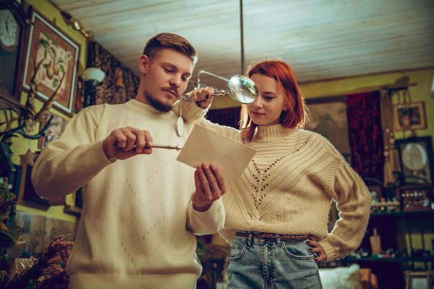 Divertido. Familia sonriente, pareja caucásica en busca de decoración del hogar y regalos de vacaciones en la tienda del hogar. Cosas elegantes y retro para saludos o diseño. Renovación interior, celebrando el tiempo.