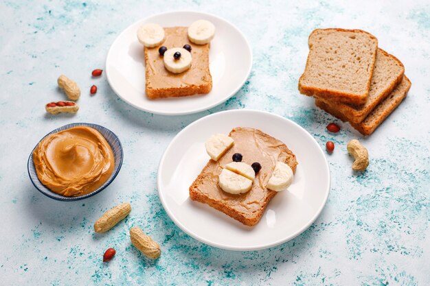 Divertido sandwich de cara de oso y mono con mantequilla de maní, plátano y grosella negra, vista superior